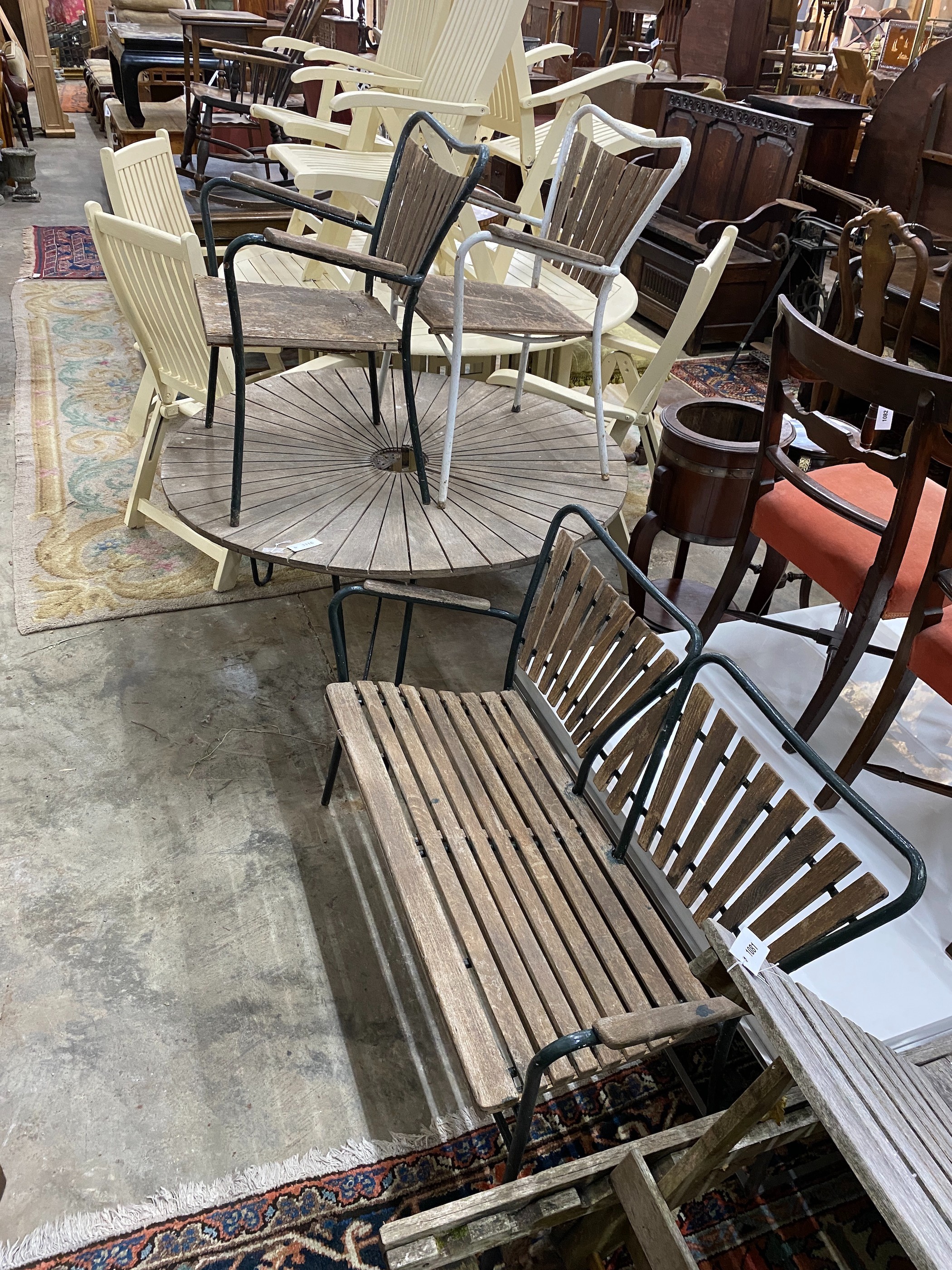 A 1950's slatted wood and wrought iron circular garden table, diameter 180cm, height 62cm, together with two elbow chairs and a bench seat